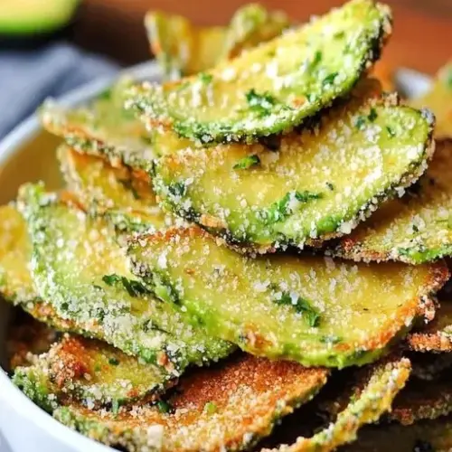 Bowl of homemade crispy avocado chips on a wooden table