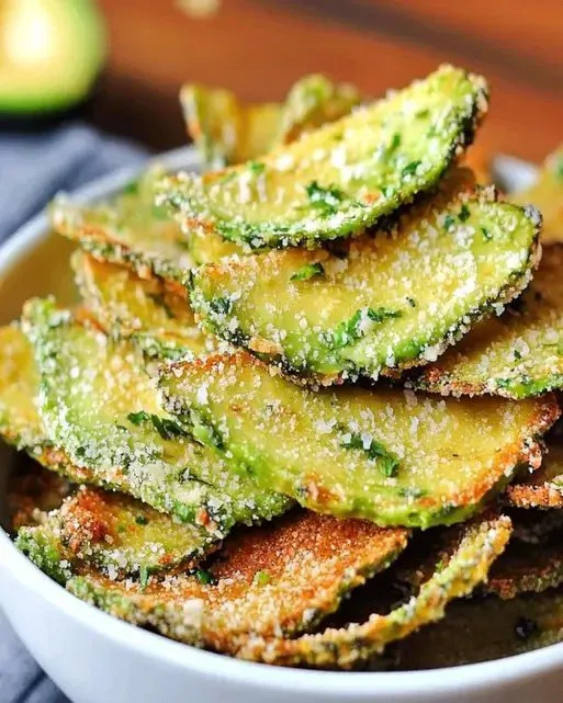 Bowl of homemade crispy avocado chips on a wooden table
