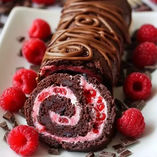 Decadent raspberry chocolate Swiss roll topped with fresh raspberries and chocolate drizzle.